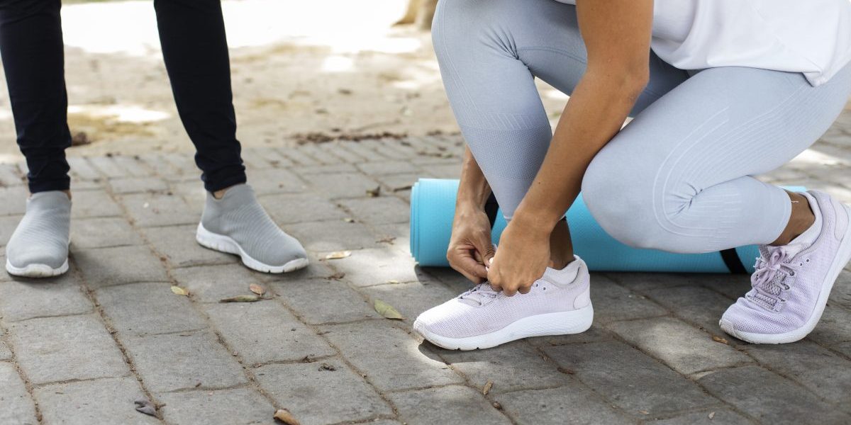 Vrouw strikt de veters van haar sportschoenen in het park